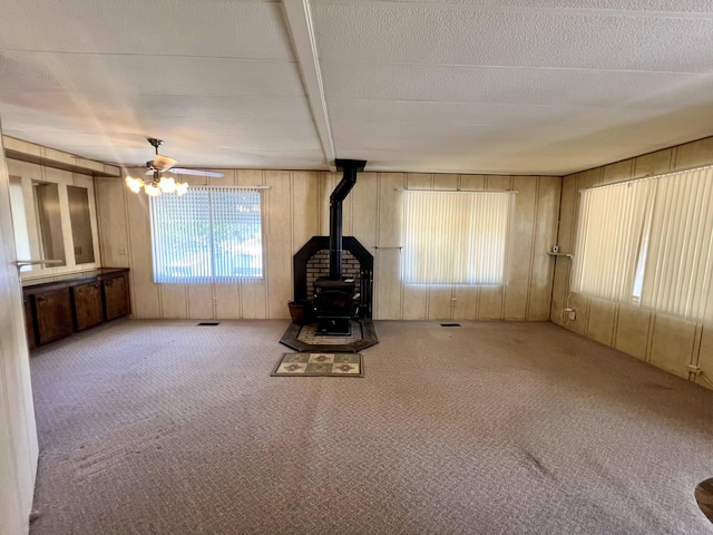 4784 White River Dr, Redding, CA 96003 - unfurnished living room with a wood stove, a ceiling fan, carpet, and wood walls