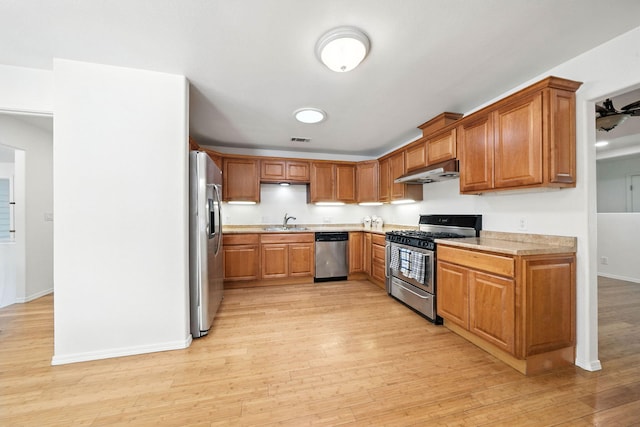 3351 Nicolet Ln, Redding, CA 96001 - kitchen with stainless steel appliances, under cabinet range hood, light countertops, light wood finished floors, and brown cabinets