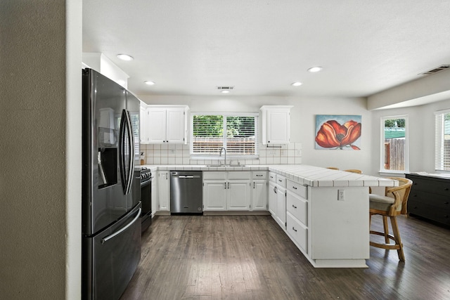 3385 Pioneer Ln, Redding, CA 96001 - kitchen featuring stainless steel appliances, a peninsula, tile countertops, a breakfast bar area, and backsplash