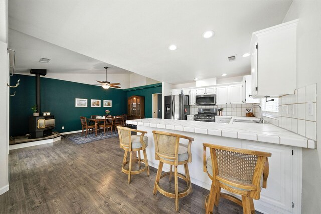 3385 Pioneer Ln, Redding, CA 96001 - kitchen featuring appliances with stainless steel finishes, tile counters, a wood stove, a peninsula, and tasteful backsplash