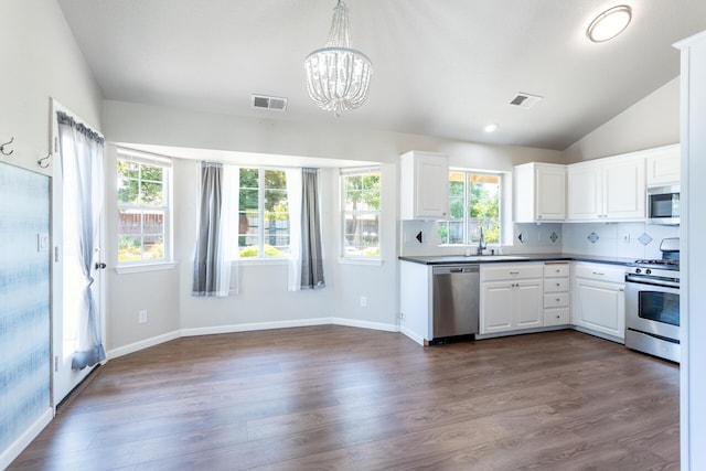 2773 Crystal Tree Dr, Redding, CA 96001 - kitchen with stainless steel appliances, a chandelier, dark countertops, white cabinetry, and lofted ceiling