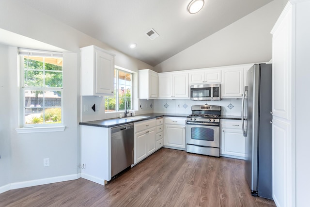 2773 Crystal Tree Dr, Redding, CA 96001 - kitchen with appliances with stainless steel finishes, dark countertops, lofted ceiling, white cabinetry, and plenty of natural light