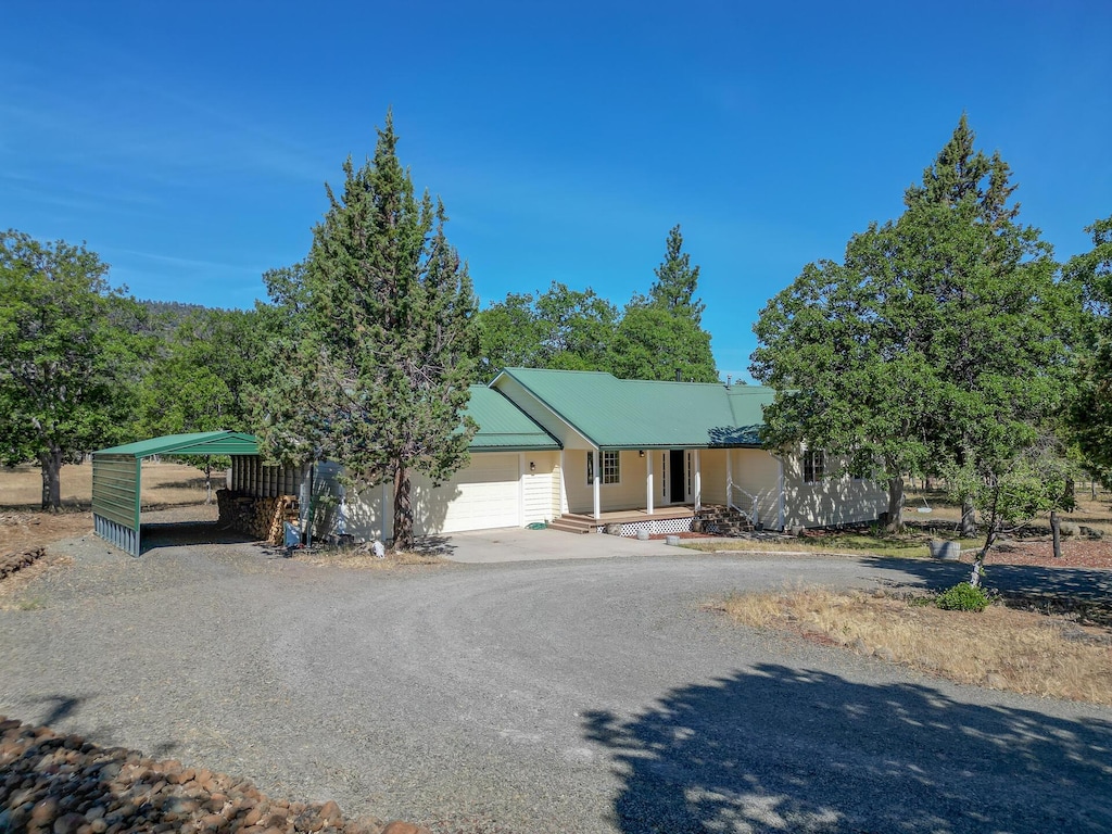43050 Shoshoni Loop, Fall River Mills, CA 96028 - view of front of home featuring driveway, covered porch, a garage, a detached carport, and a metal roof