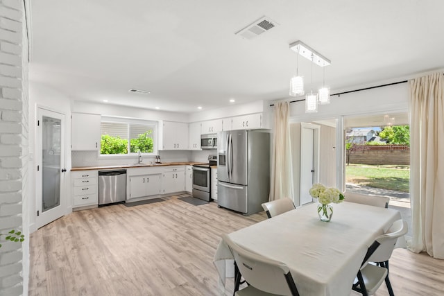 4135 Oro St, Redding, CA 96001 - kitchen featuring appliances with stainless steel finishes, white cabinetry, light wood-type flooring, pendant lighting, and recessed lighting