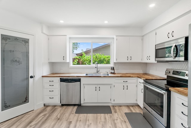 4135 Oro St, Redding, CA 96001 - kitchen with appliances with stainless steel finishes, wooden counters, tasteful backsplash, white cabinets, and light wood-style flooring