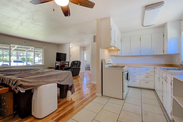 37153/55 Siskiyou St, Burney, CA 96028 - kitchen featuring white range with gas stovetop, light countertops, open floor plan, a ceiling fan, and white cabinets