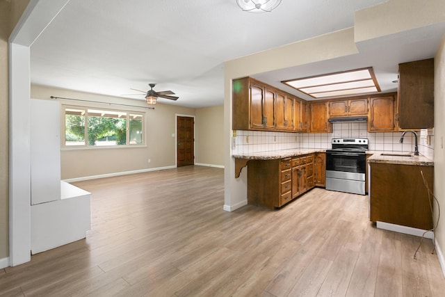 5858 Deschutes Rd, Anderson, CA 96007 - kitchen with stainless steel range with electric stovetop, under cabinet range hood, brown cabinetry, ceiling fan, and light wood-type flooring