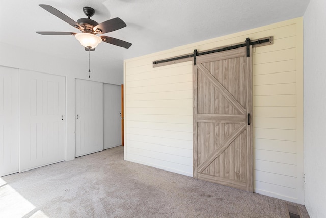 5858 Deschutes Rd, Anderson, CA 96007 - unfurnished bedroom with carpet floors, a barn door, two closets, wooden walls, and ceiling fan