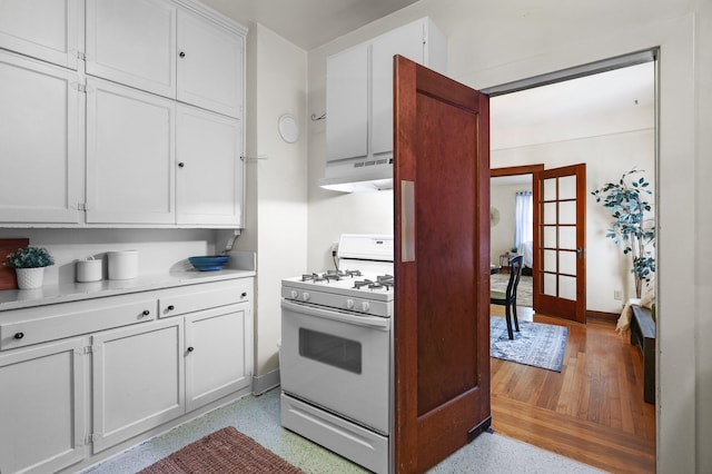 21552157 Butte St, Redding, CA 96003 - kitchen featuring white gas stove, under cabinet range hood, french doors, white cabinets, and light countertops