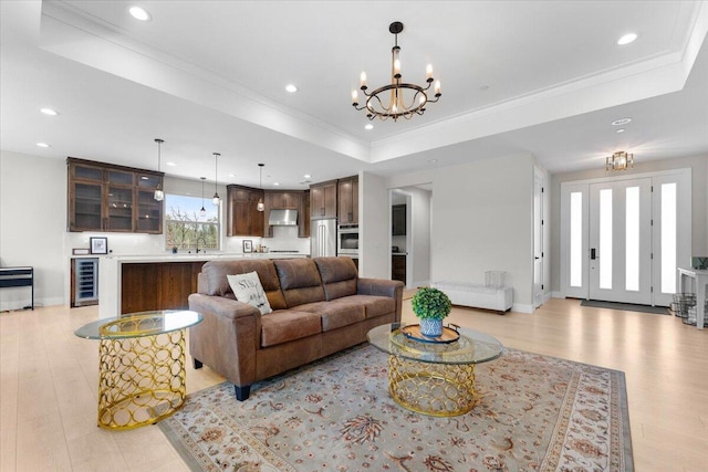 16520 Blarney Ln, Redding, CA 96001 - living room with wine cooler, a chandelier, a tray ceiling, recessed lighting, and light wood-type flooring