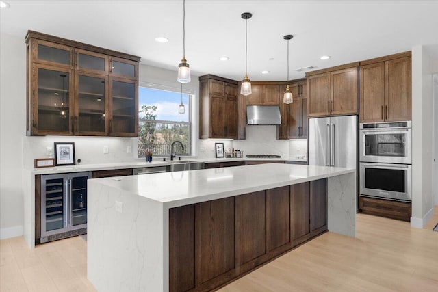 16520 Blarney Ln, Redding, CA 96001 - kitchen featuring beverage cooler, double oven, exhaust hood, light wood-type flooring, and light countertops