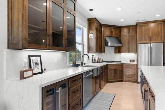 16520 Blarney Ln, Redding, CA 96001 - kitchen with beverage cooler, wall chimney range hood, appliances with stainless steel finishes, hanging light fixtures, and light wood-type flooring