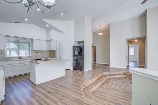 1633 Wee Burn Ct, Redding, CA 96003 - kitchen with freestanding refrigerator, high vaulted ceiling, light countertops, a center island, and decorative backsplash