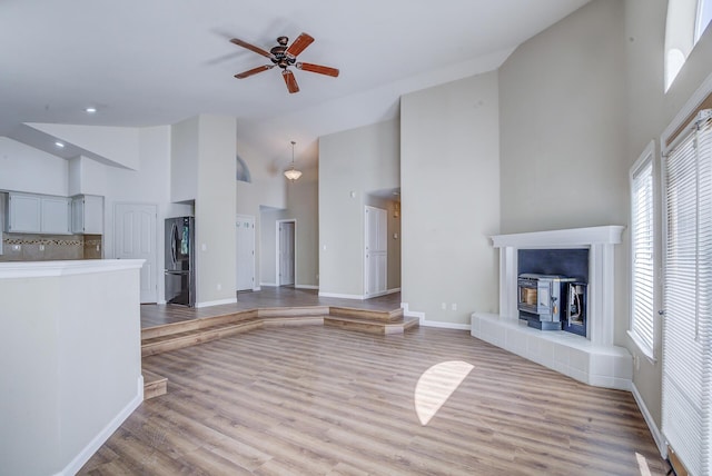 1633 Wee Burn Ct, Redding, CA 96003 - unfurnished living room featuring high vaulted ceiling, a wood stove, plenty of natural light, ceiling fan, and light wood-type flooring