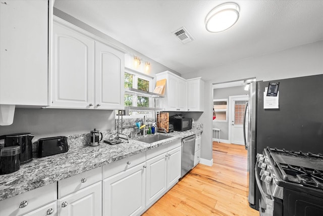 678 W St, Redding, CA 96001 - kitchen with stainless steel appliances, white cabinets, and light wood-style flooring