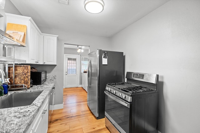 678 W St, Redding, CA 96001 - kitchen with stainless steel appliances, white cabinetry, light wood finished floors, and light stone countertops