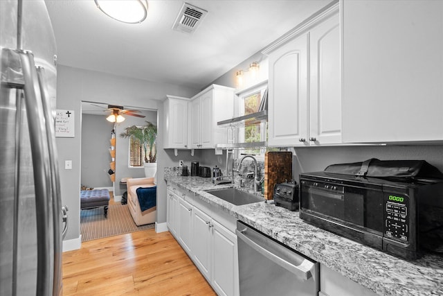 678 W St, Redding, CA 96001 - kitchen featuring appliances with stainless steel finishes, light wood finished floors, white cabinets, a ceiling fan, and light stone counters