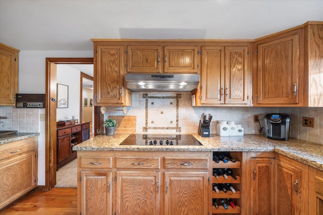 19396 Natalie Way, Redding, CA 96003 - kitchen with under cabinet range hood, black electric stovetop, decorative backsplash, light wood-style flooring, and light stone countertops