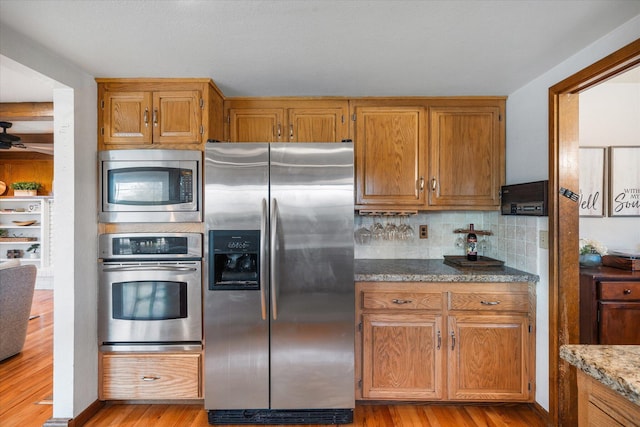 19396 Natalie Way, Redding, CA 96003 - kitchen with stainless steel appliances, light wood-style floors, backsplash, and brown cabinetry