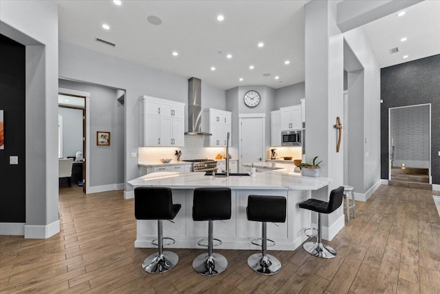 19580 Mockingbird Ln, Redding, CA 96002 - kitchen with wall chimney range hood, appliances with stainless steel finishes, white cabinetry, light wood-style floors, and recessed lighting
