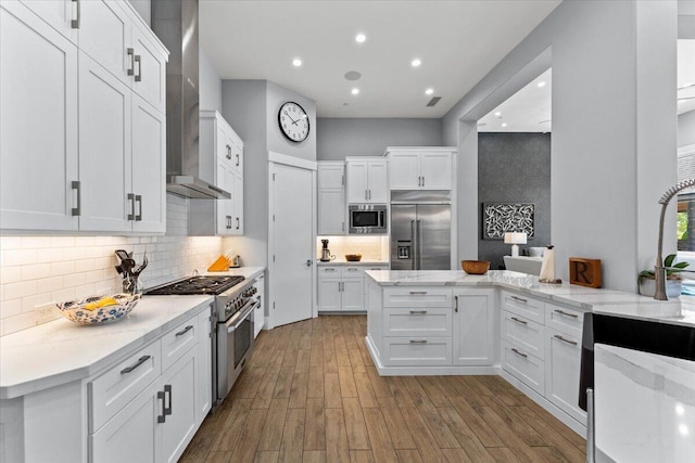 19580 Mockingbird Ln, Redding, CA 96002 - kitchen featuring built in appliances, wall chimney range hood, white cabinets, wood finished floors, and decorative backsplash