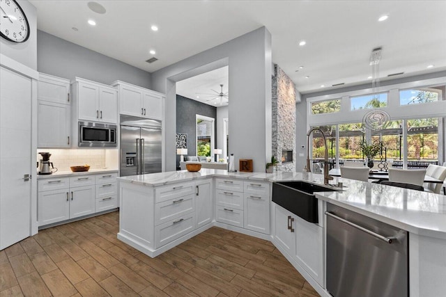 19580 Mockingbird Ln, Redding, CA 96002 - kitchen featuring built in appliances, a peninsula, white cabinets, recessed lighting, and tasteful backsplash
