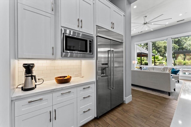19580 Mockingbird Ln, Redding, CA 96002 - kitchen with built in appliances, backsplash, dark wood-style floors, white cabinetry, and light stone counters