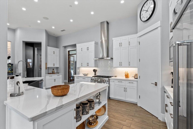 19580 Mockingbird Ln, Redding, CA 96002 - kitchen with wall chimney range hood, stainless steel range, decorative backsplash, light wood-type flooring, and white cabinetry