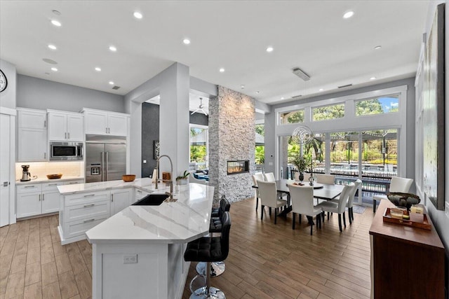 19580 Mockingbird Ln, Redding, CA 96002 - kitchen with built in appliances, a stone fireplace, a spacious island, light wood-style floors, and recessed lighting