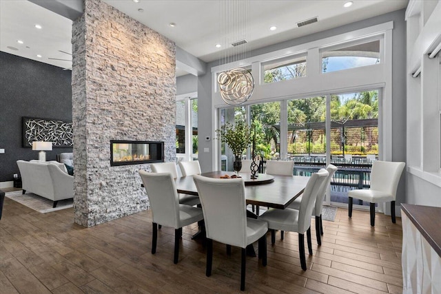 19580 Mockingbird Ln, Redding, CA 96002 - dining space featuring wood-type flooring, recessed lighting, a stone fireplace, a towering ceiling, and an accent wall