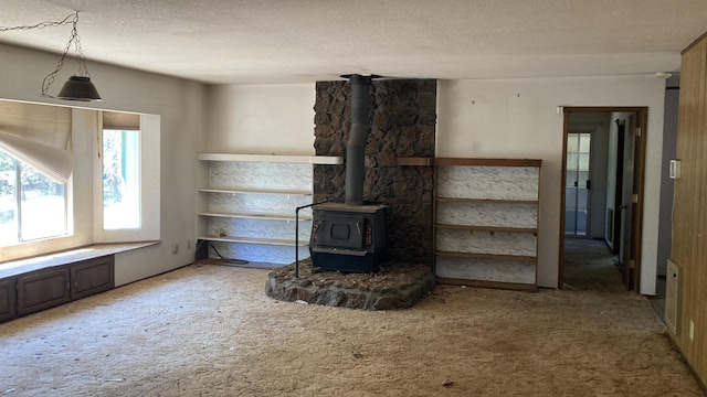 770 Day Rd, Mcarthur, CA 96056 - unfurnished living room with a textured ceiling, a wood stove, and light colored carpet