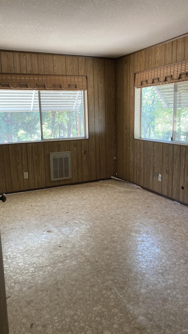 770 Day Rd, Mcarthur, CA 96056 - empty room featuring healthy amount of natural light, wood walls, an AC wall unit, and a textured ceiling
