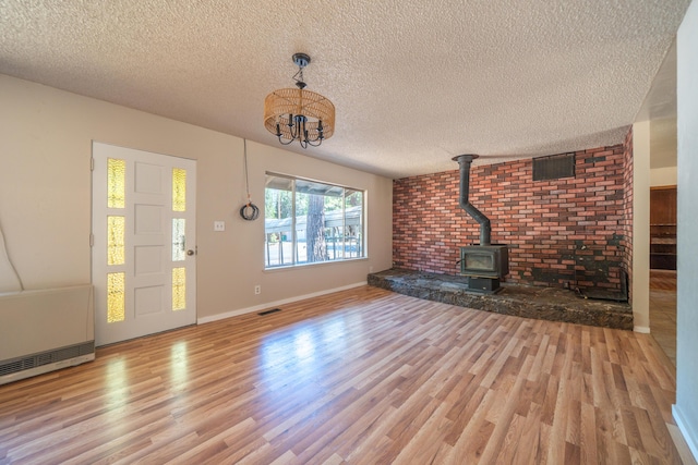 37347 Cypress Ave, Burney, CA 96013 - unfurnished living room with a wood stove, a textured ceiling, wood finished floors, and a chandelier