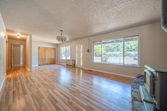 37347 Cypress Ave, Burney, CA 96013 - unfurnished living room featuring light wood-type flooring, a chandelier, and a textured ceiling