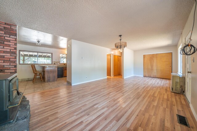 37347 Cypress Ave, Burney, CA 96013 - unfurnished living room with a wood stove, a textured ceiling, light wood finished floors, and a chandelier