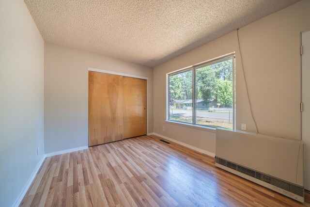 37347 Cypress Ave, Burney, CA 96013 - unfurnished bedroom with light wood-style floors, a closet, and a textured ceiling