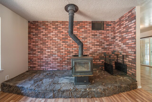 37347 Cypress Ave, Burney, CA 96013 - detailed view of a textured ceiling, a wood stove, wood finished floors, and brick wall