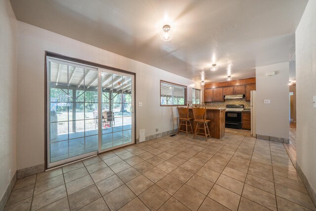37347 Cypress Ave, Burney, CA 96013 - kitchen featuring black range with electric cooktop, under cabinet range hood, tasteful backsplash, a peninsula, and brown cabinets