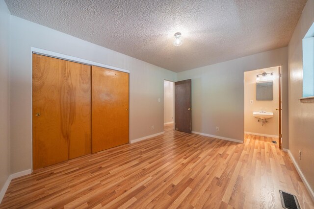 37347 Cypress Ave, Burney, CA 96013 - unfurnished bedroom featuring light wood finished floors, a closet, a textured ceiling, and ensuite bath