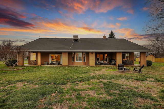 3010 Mateo Ct, Anderson, CA 96007 - back of property at dusk featuring a patio, stucco siding, a lawn, and an outdoor fire pit