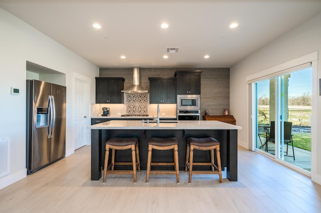 6538 Bandito Dr, Redding, CA 96003 - kitchen with stainless steel appliances, wall chimney exhaust hood, decorative backsplash, recessed lighting, and a kitchen island with sink
