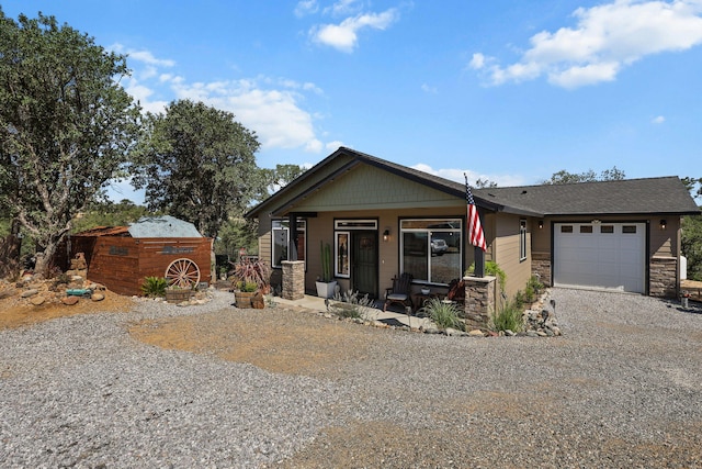 18710 Saddleback Ridge Rd, Cottonwood, CA 96022 - view of front of home with gravel driveway, a garage, covered porch, stone siding, and a shed