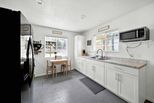 3075 Forest Hills Dr, Redding, CA 96002 - kitchen featuring stainless steel microwave, freestanding refrigerator, light countertops, white cabinets, and a textured ceiling