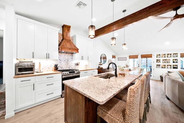 3075 Forest Hills Dr, Redding, CA 96002 - kitchen with stainless steel range with gas stovetop, custom range hood, backsplash, light wood-style flooring, and open floor plan