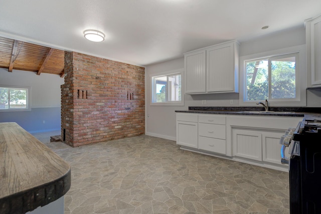 12194 Lake Blvd, Redding, CA 96001 - kitchen featuring stove, stone floors, brick wall, white cabinets, and a wooden ceiling with exposed beams