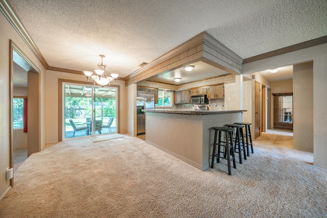 2076 Merle Dr, Redding, CA 96001 - kitchen featuring stainless steel appliances, crown molding, light carpet, a chandelier, and a peninsula