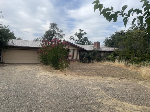 1110 Dusty Ln, Redding, CA 96002 - view of side of property featuring dirt driveway, a chimney, and an attached garage
