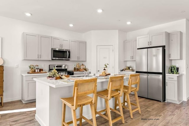 876 Wind Cove Dr, Redding, CA 96001 - kitchen with stainless steel appliances, light countertops, light wood finished floors, a kitchen breakfast bar, and a center island with sink