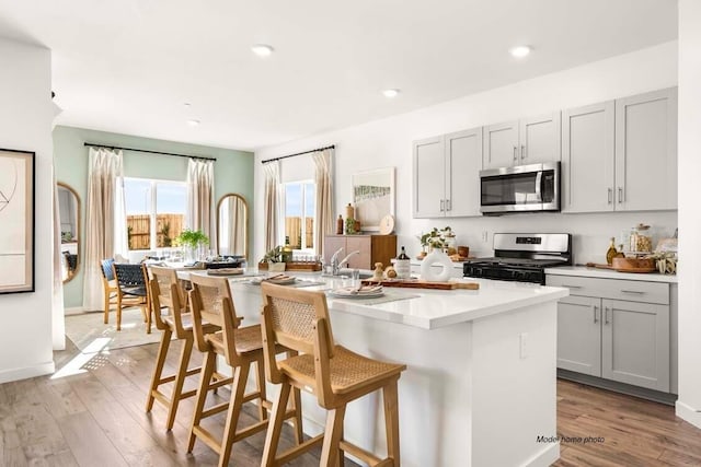 876 Wind Cove Dr, Redding, CA 96001 - kitchen featuring stainless steel microwave, gas range, gray cabinetry, a center island with sink, and recessed lighting