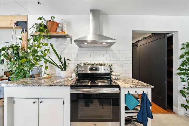1448 Carter Way, Redding, CA 96002 - kitchen featuring electric range, wall chimney range hood, decorative backsplash, light stone counters, and a barn door